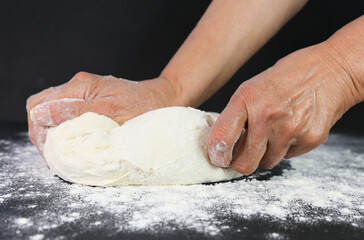 Woman's hands knead the dough for baking bread. The chef. Close-up of woman's hands kneading dough