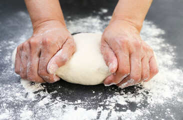 Woman's hands knead the dough for baking bread. The chef. Close-up of woman's hands kneading dough