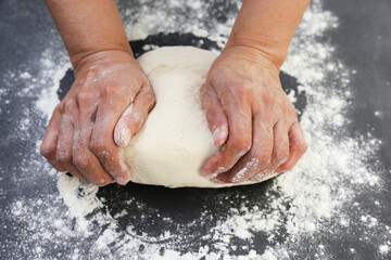 Woman's hands knead the dough for baking bread. The chef. Close-up of woman's hands kneading dough