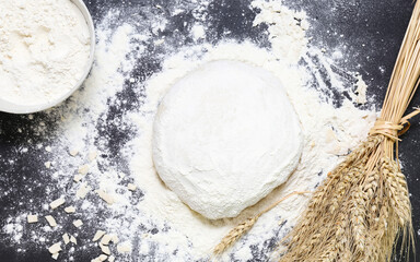 Raw dough flour and ears of wheat on black background top view Home baking concept