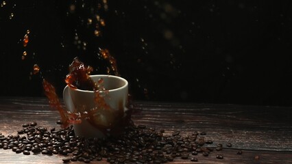 Super slow motion of falling ice dropping in to coffee cup and splashing with black separated background. Close up of sugar drop in espresso surrounded by pile of coffee bean. Motion shot. Comestible.