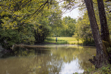 Fototapeta premium Young man, a freshwater fisherman holding a fishing rod with a spinning reel, getting ready to catch a fish. Fishing equipment and skills concepts.