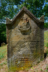 stary nagrobek na kamiennej płycie pokryty patyną,  stary nagrobek z piaskowca, patina covered sandstone tombstone in shade on sunny day