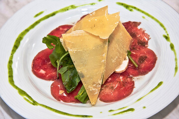 Meat Carpaccio with Parmesan Cheese, Arugula and Mushrooms on white plate, Deli food
