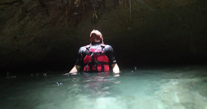 Tilt from hole in cave ceiling to lonely man in water
