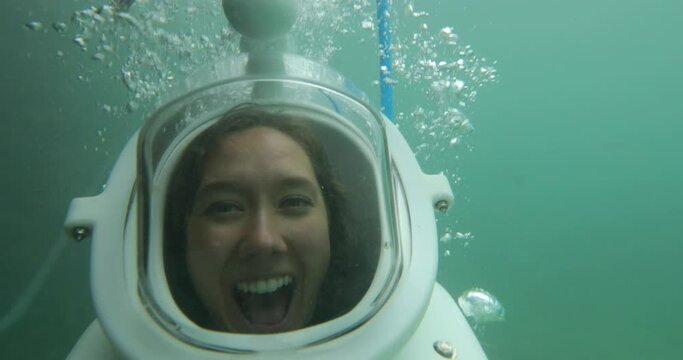 Laughing woman underwater with helmet on - close up