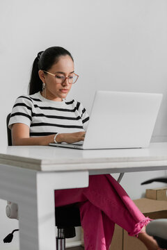 Concentrated Latin American woman working at a desk with laptop