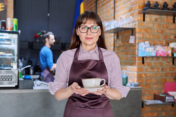 Woman in apron, food service coffee shop worker, small business owner with cup of coffee