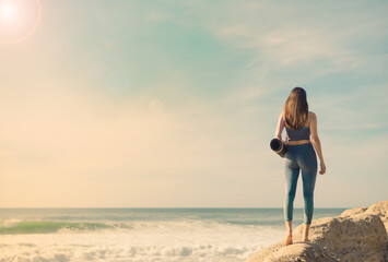 A girl is preparing to practice outdoor yoga on the ocean. Calmness and relax. Background with ocean view and yoga trainer.