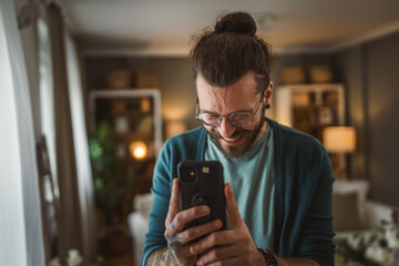 Adult man take a pictures of himself with mobile phone tattoos at home