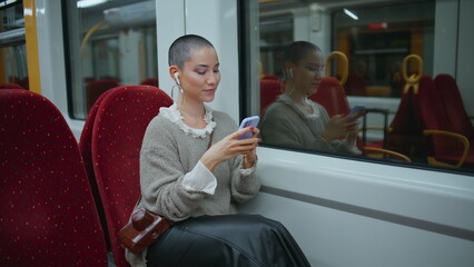 Girl voyager messaging smartphone sitting modern train. Short hair woman texting