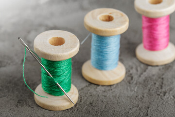 wooden spools with colored threads and a sharp needle.