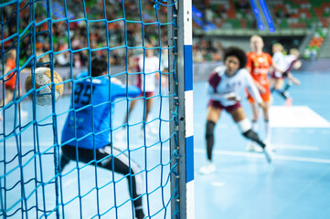 Detail of handball goal post with net and game in the background. - obrazy, fototapety, plakaty
