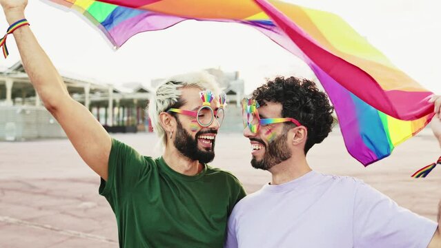 Happy young gay couple waving the LGBT rainbow flag at the pride day parade. Lesbian, gay, bisexual, transgender social movements. Concept of happiness freedom love same-sex couple