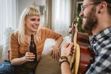 Adult couple enjoy at home play guitar and drink beer happy together