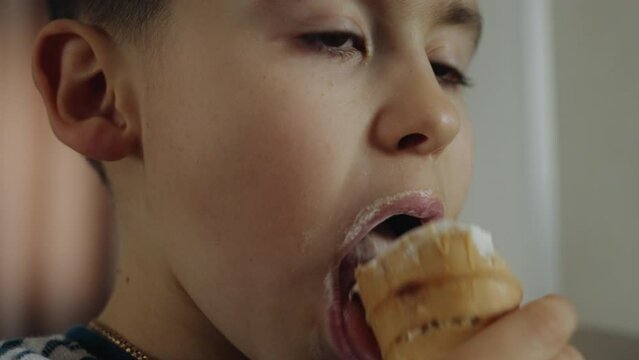 Happy boy eating vanilla ice cream outdoors in home at vacation. Child licking icecream refreshing in heat. Summer cooling off.
