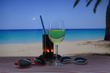 On South Beach, a glass of wine and a drink sit on a table next to a night cafe.