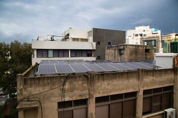 Solar panels atop urban buildings in Ramat Gan, Israel, under impending rainclouds