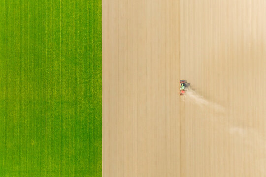 Agricultural transport. Tractor in the field. Working the land. Aerial view of the field. Landscape from a drone. Light and shadow. Natural background from drone. View from above. Agriculture.