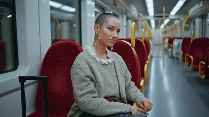 Trendy businesswoman posing train seat looking camera confidently zoom out.