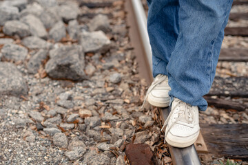 Close up legs in white sneakers walking on a railway track