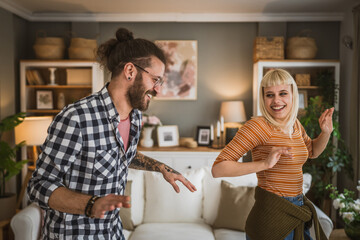 One adult couple dance together and have fun at living room at home