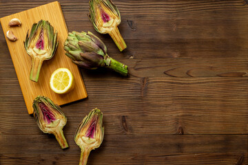 Green artichokes heads with ingredients garlic and lemon. Cooking background