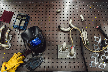 Welder's workplace. Welding equipment on an iron table with a welding helmet, leather gloves, a...