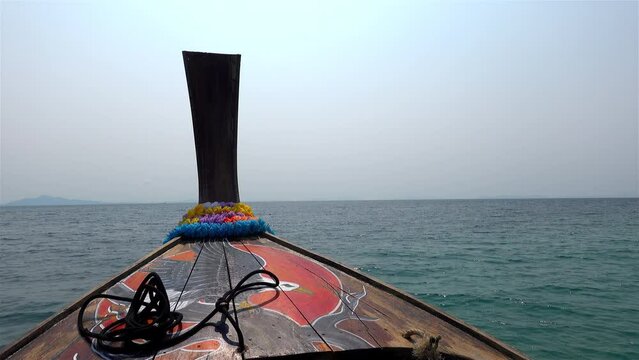 bow of a Thai long boat motoring towards the horizon