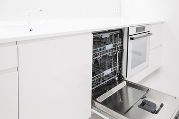 Washing machine with opened door at modern kitchen interior