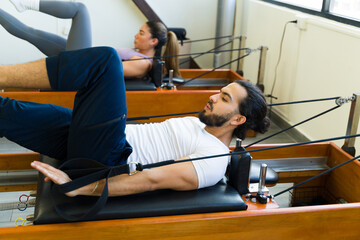 Man performing pilates on reformer bed - 785738062