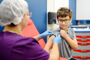 A boy is being vaccinated. A child is given a vaccine during an epidemic or outbreak of a disease. - obrazy, fototapety, plakaty