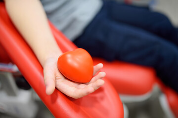 A nurse takes blood from a child. Close up view of kid hand with a bouncy heart shape ball during of taking a blood sample for examination in a modern laboratory or hospital. - 785739027