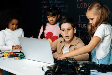 In classroom student in STEM class learning about coding robotics car. Brown shirt Schoolboy and...