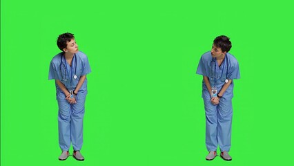 Medical assistant being impatient against greenscreen backdrop, looking around and waiting for patients at consultations. Nurse with health expertise feeling frustrated while she waits. Camera A. - obrazy, fototapety, plakaty