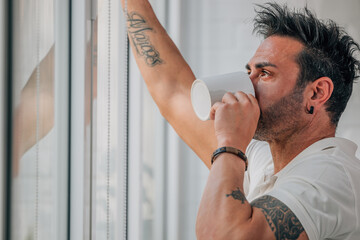 attractive man with beard drinking coffee at the window