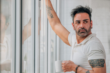 attractive man with beard drinking coffee at the window