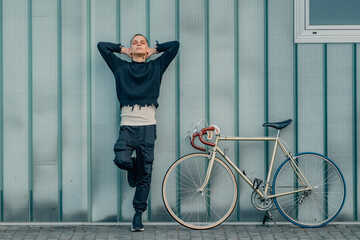 young man with bicycle relaxed with street wall background and copy-space