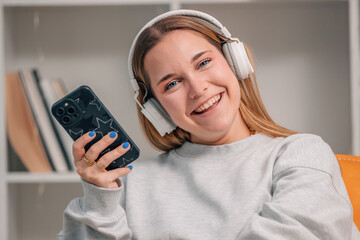 girl or young woman at home smiling with mobile phone and headphones - 785745244