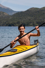 Young man enjoying kayaking during his summer vacation in the lakes of southern Argentina, San Carlos de Bariloche, Patagonia.