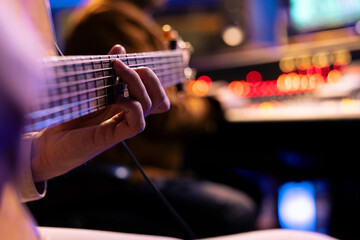 Talented singer playing new accords on electro acoustic guitar in music studio, recording new songs...