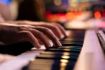 Musician playing electronic keyboard synthesizer in professional studio, creating songs and working with producer on new album. Talented singer composing music on electronic keyboard. Close up.