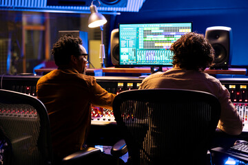 Professional sound engineer and artist working together on a new track, using digital audio...