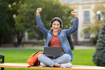 Excited woman student with laptop celebrating success