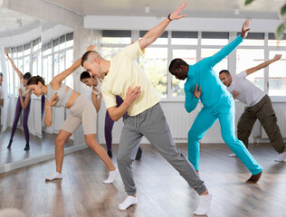 Active young man practicing hip-hop dance in training hall during dancing classes