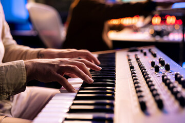 Male artist playing notes on electronic midi controller in studio, composing a new song with piano...