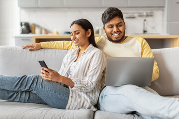Content Indian couple using tech at home