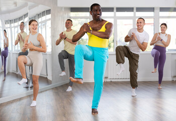 During dance workshop, African man with team of like-minded multinational people learn to perform...
