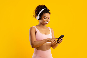 Fit african american lady with headphones using smartphone