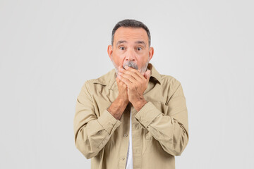 Elderly man covering mouth in surprise on white